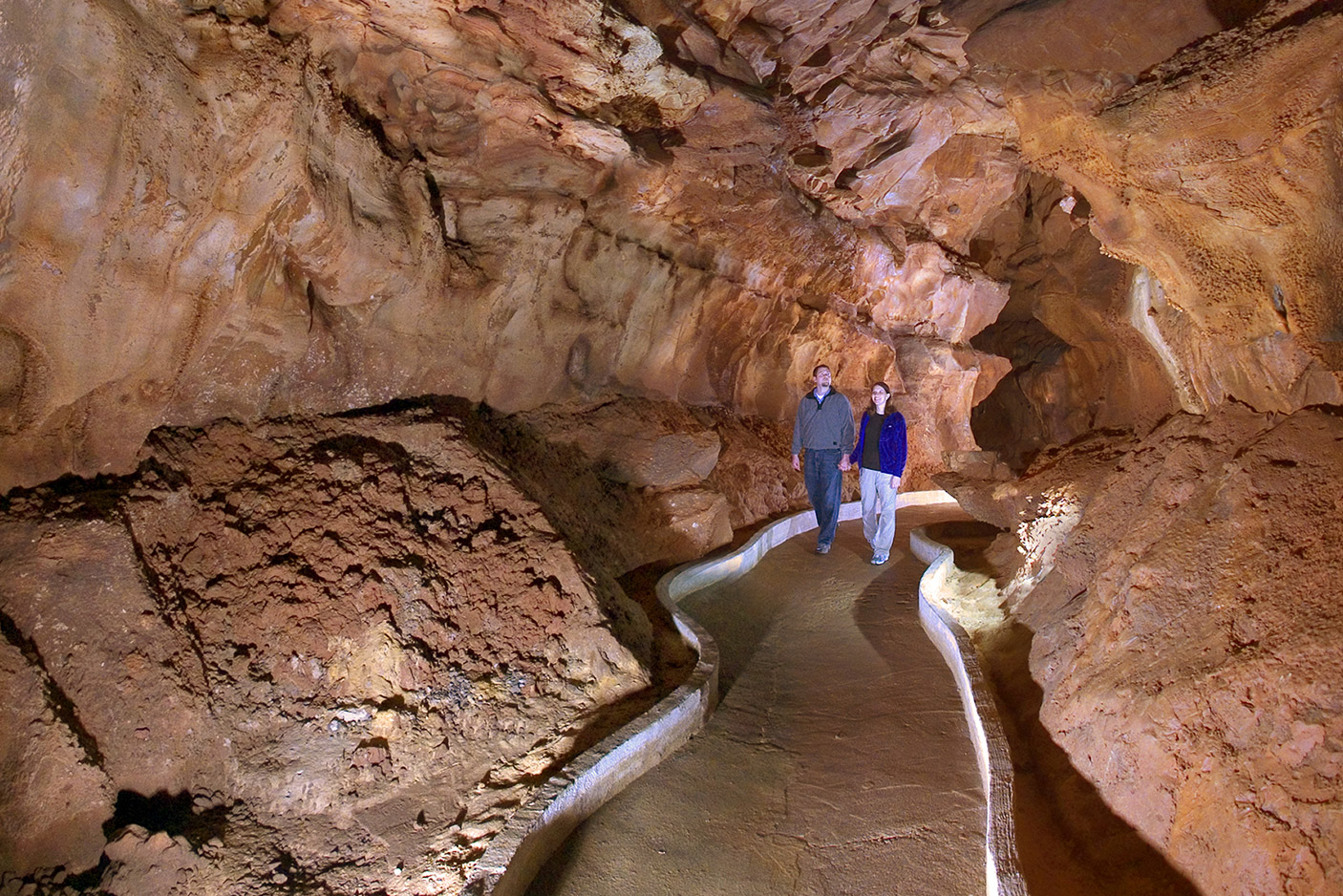 couple holding hands walking in cave